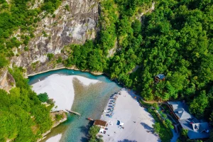 Top-down view of Shala River with clear turquoise water winding through dramatic mountain landscape in Albania