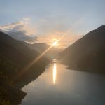 Berisha River campsite with sunset over the lake, surrounded by majestic mountains.