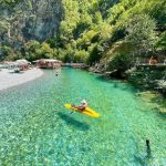 Tourist canoeing on the crystal-clear waters of Shala River surrounded by lush greenery.