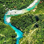 Aerial view of the crystal-clear waters of Shala River surrounded by mountains.