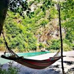 Hammock by Shala River with serene views of crystal-clear water and lush greenery.