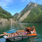 North Albania Boat filled with tourists docking at Berisha River camping location in Albania.