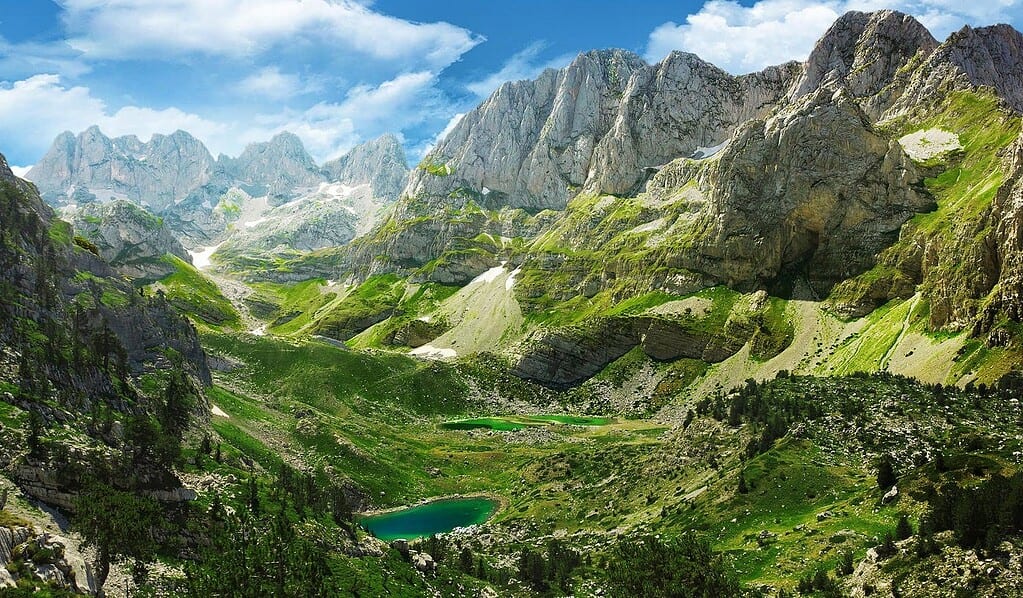 Albanian Alps mountain valley with turquoise lake limestone peaks and green meadows northern Albania