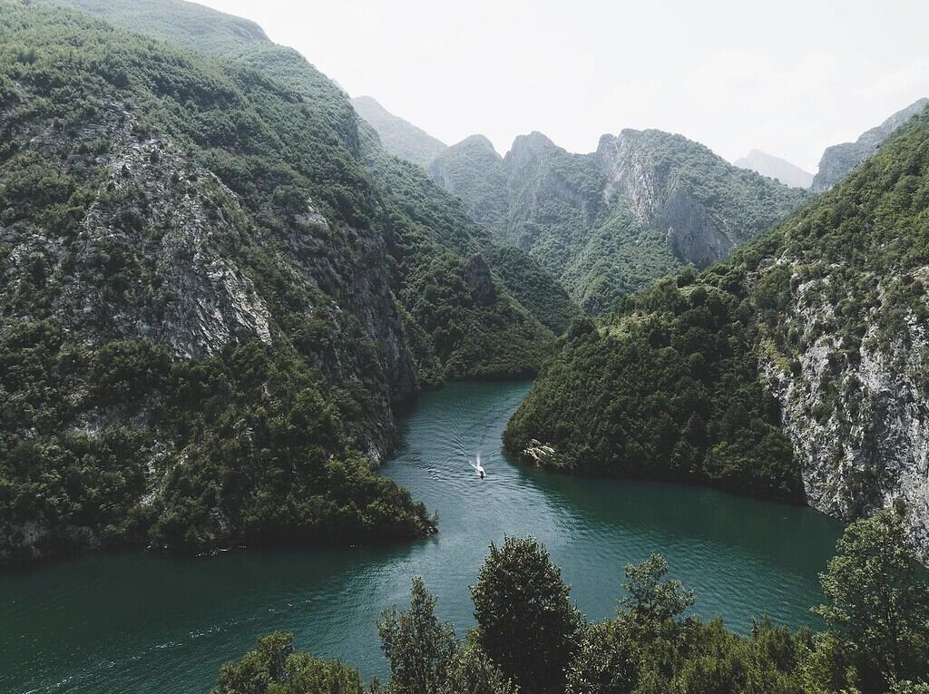 Komani Lake Albania aerial view narrow canyon turquoise water forested cliffs boat tour route