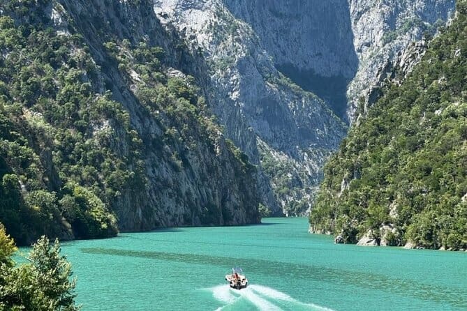 阿尔巴尼亚科马尼湖，翡翠绿松石色的水，狭窄峡谷中的小型快艇，石灰岩峭壁