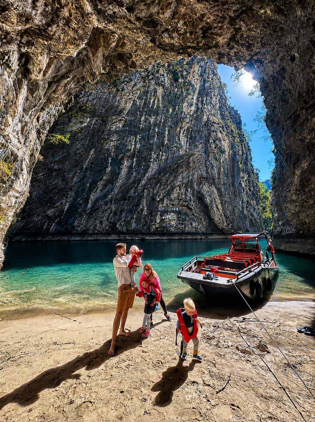 Family enjoying Komani Lake to Shala River boat tour in northern Albania with crystal clear water and mountain cliffs