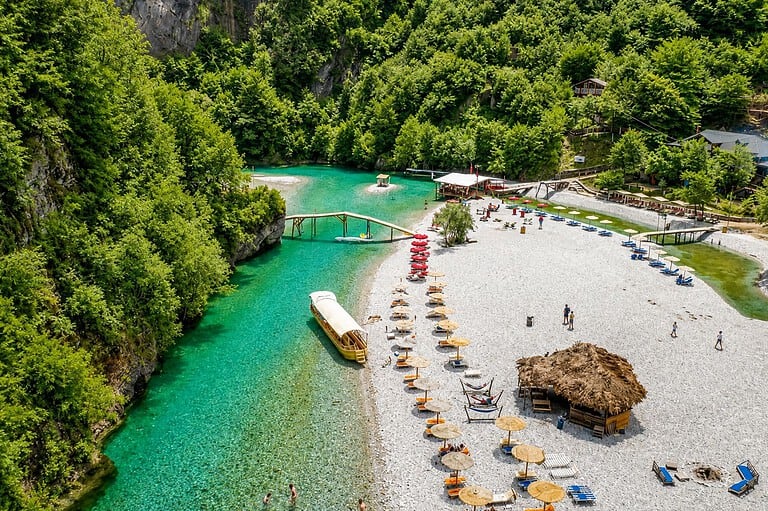 Shala River beach with turquoise water and mountain landscape during a daily boat tour from Lezhe in northern Albania