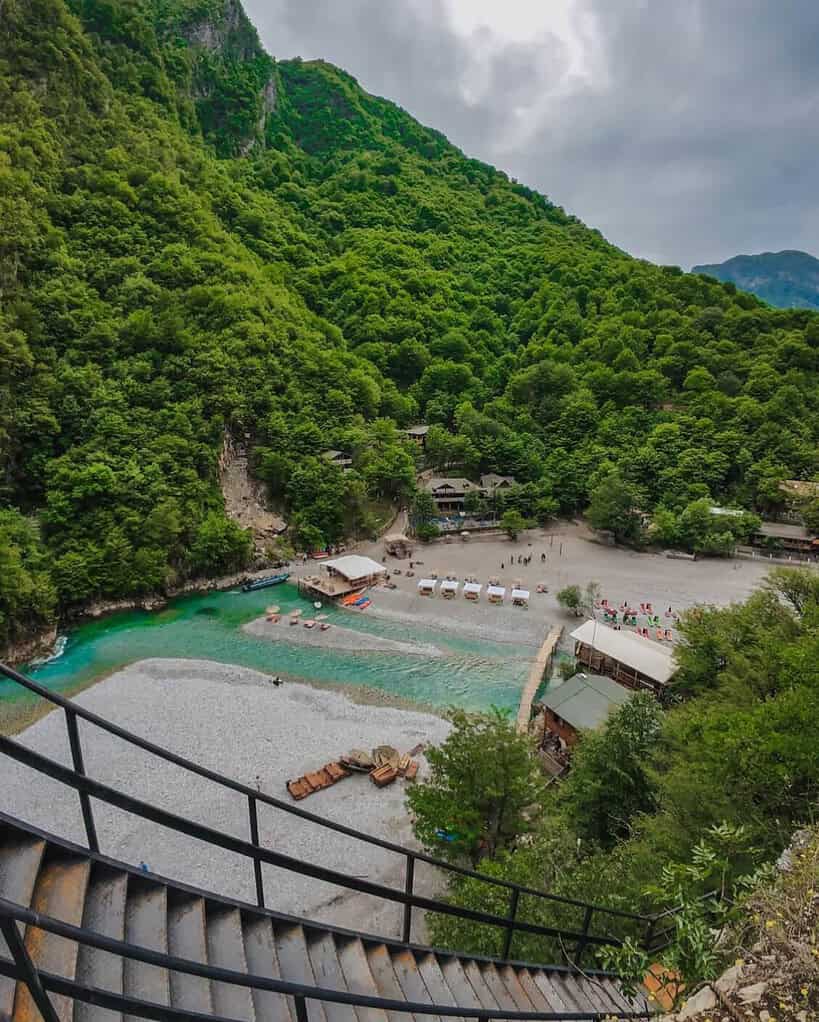 Aerial view of Shala River beach and wooden chalets from staircase as part of a day trip from Tirana