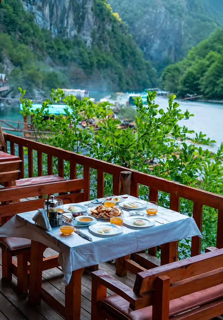 Breakfast table on a wooden balcony overlooking Shala River, Albania