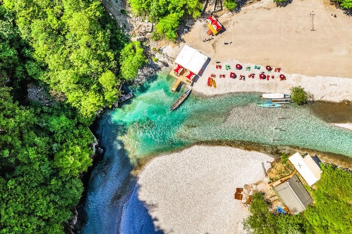 Aerial drone view of turquoise Shala River meeting pebble beach