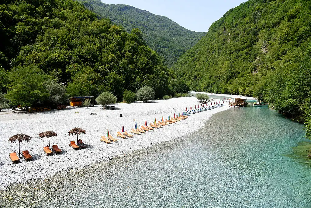 Shala River pebble beach with clear water and mountains