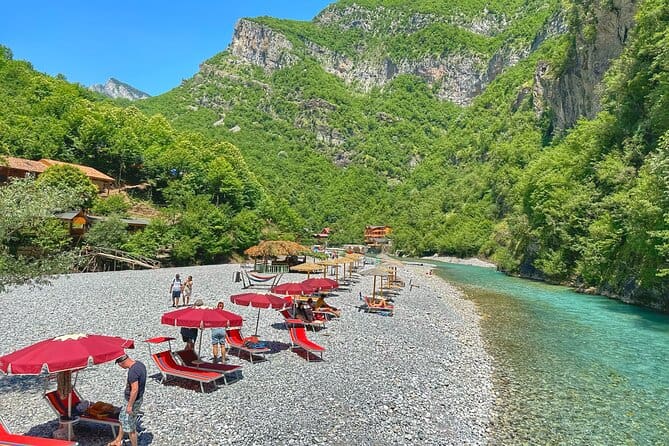 Red umbrellas and loungers on Shala River pebble beach