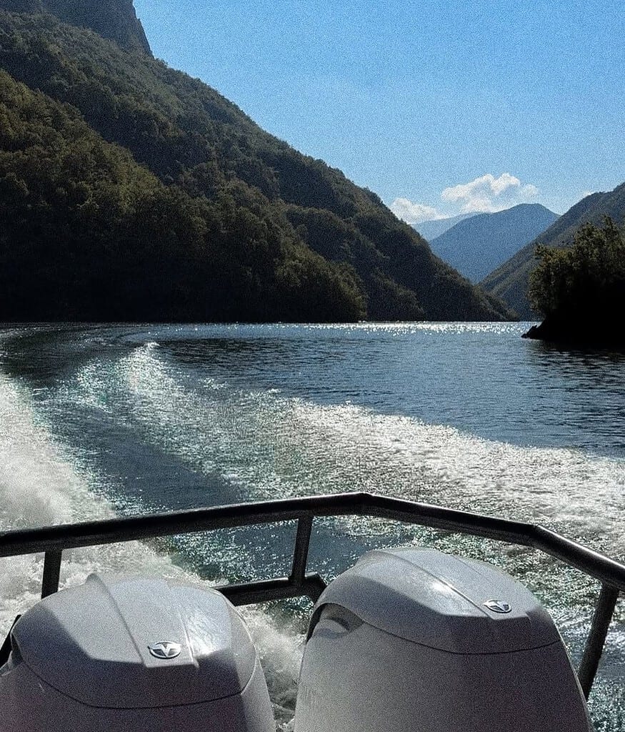 View from the back of a boat with two outboard motors and a sparkling wake on Koman Lake