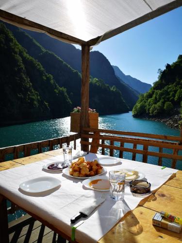 Breakfast table on a wooden terrace overlooking Komani Lake and surrounding mountains