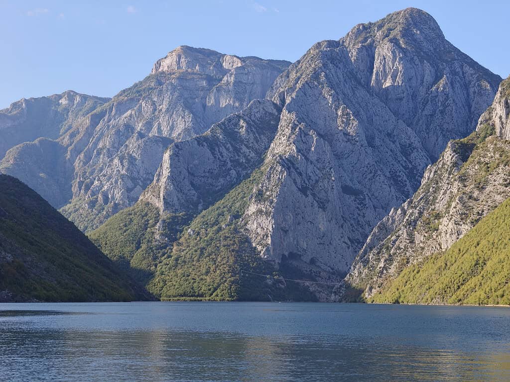 Steep limestone mountains rising above calm blue water on Koman Lake in northern Albania