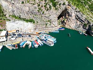 Aerial view of the Komani Lake boat dock, parking area, and tunnel entrance, Albania