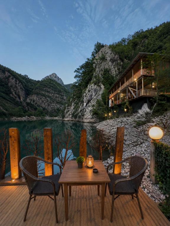 Evening terrace beside Shala River with mountain lodge and illuminated outdoor seating