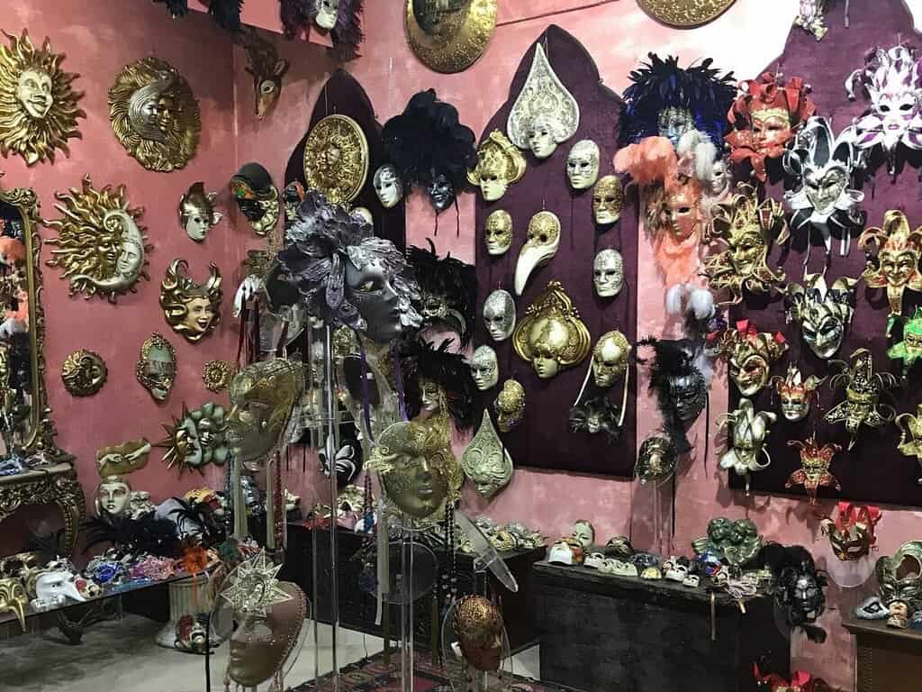 Wall display of ornate decorative masks in gold, silver and feathers in a souvenir shop