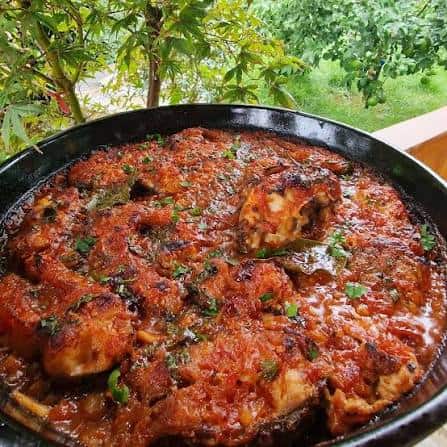 Tave krapi, baked carp with onions and fresh parsley, served in a black dish with a glass of red wine